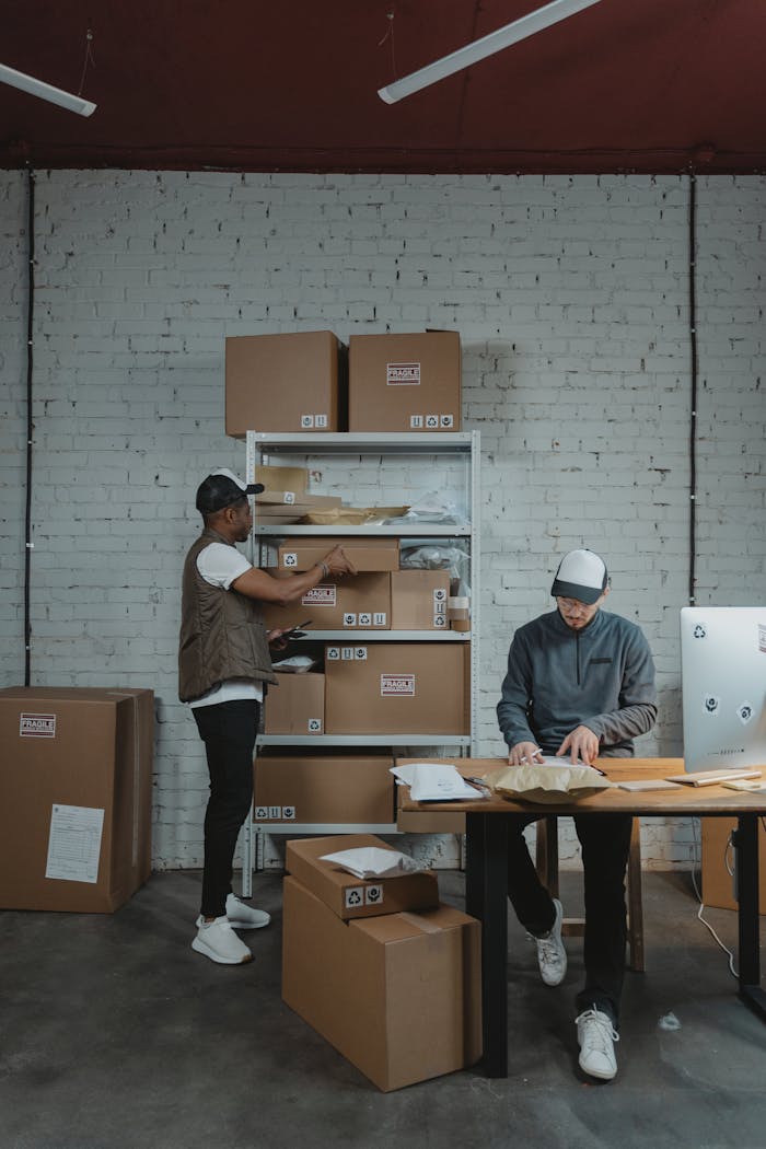 Two male workers organizing and packing boxes in a warehouse setting.